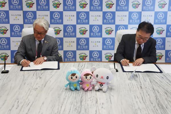 調印書に記名する星野市長と安達学長の写真