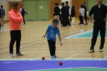 選手がボッチャボールを投げてその軌道を眺めている写真